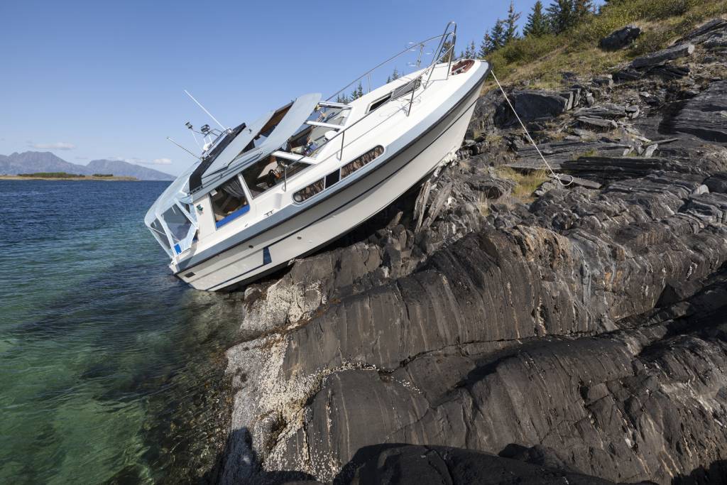 Close up photo of recreational boat after collision with coastal rocks