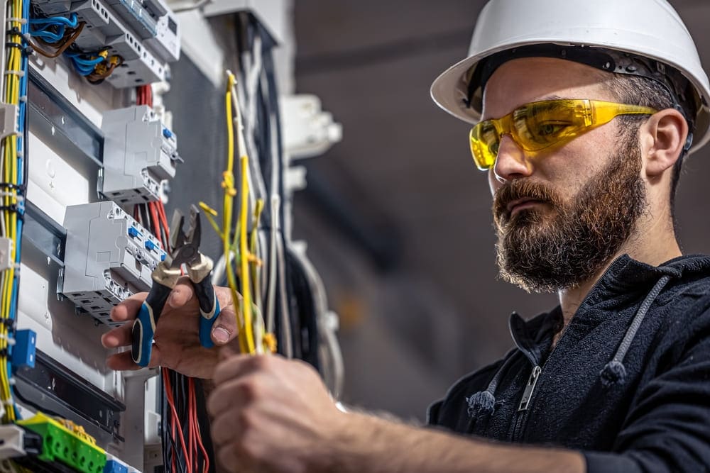 Electrician works in a switchboard with an electrical connecting cable