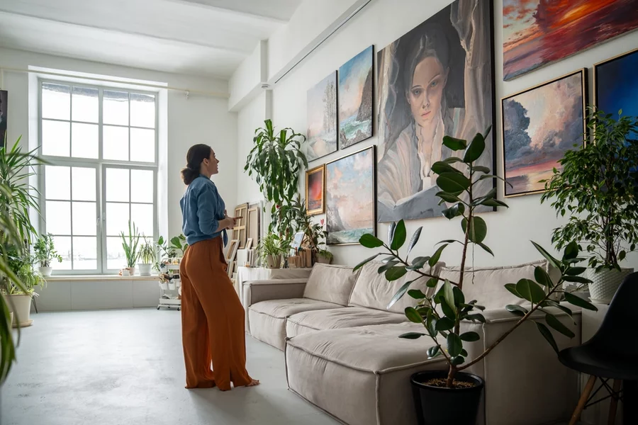 Woman looking at paintings on wall.