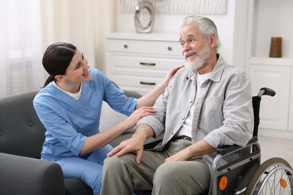 A nurse helping a senior man in a wheelchair.