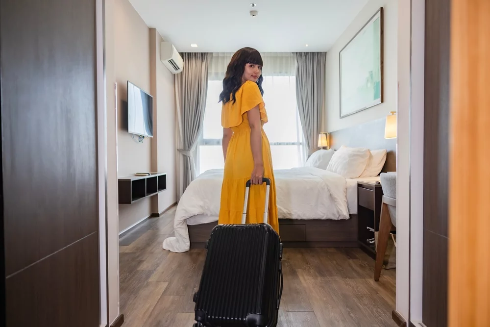 Woman entering room with suitcase