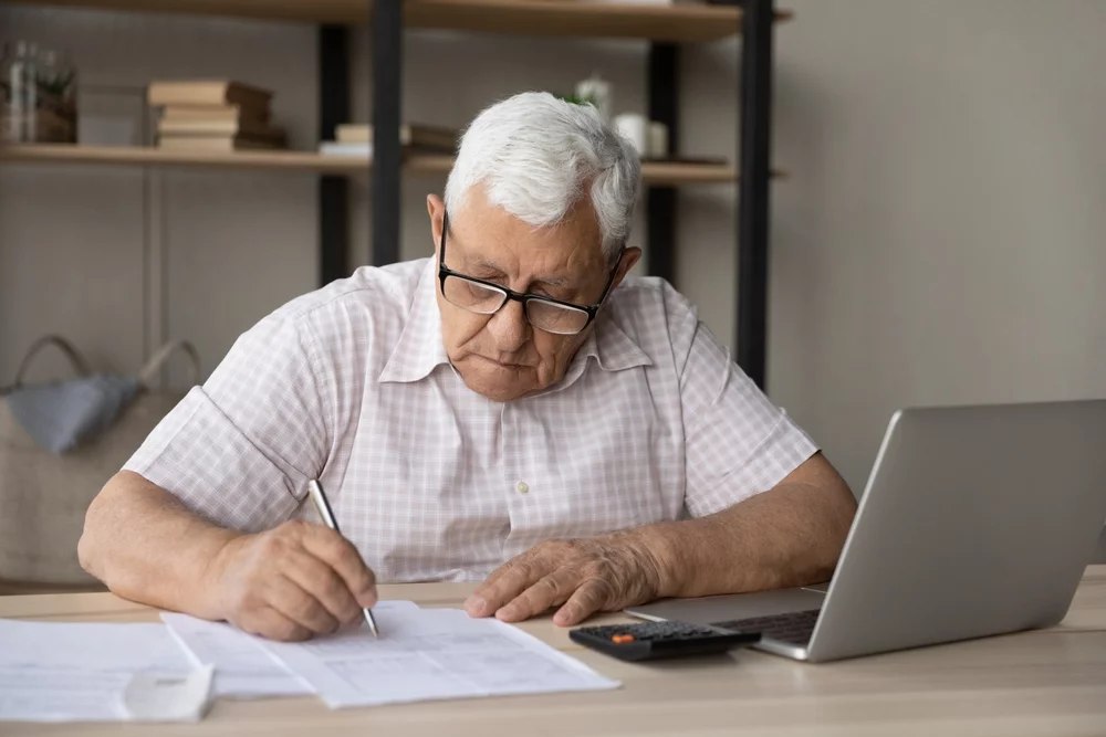 Landlord sitting at a desk writing on a contract paper